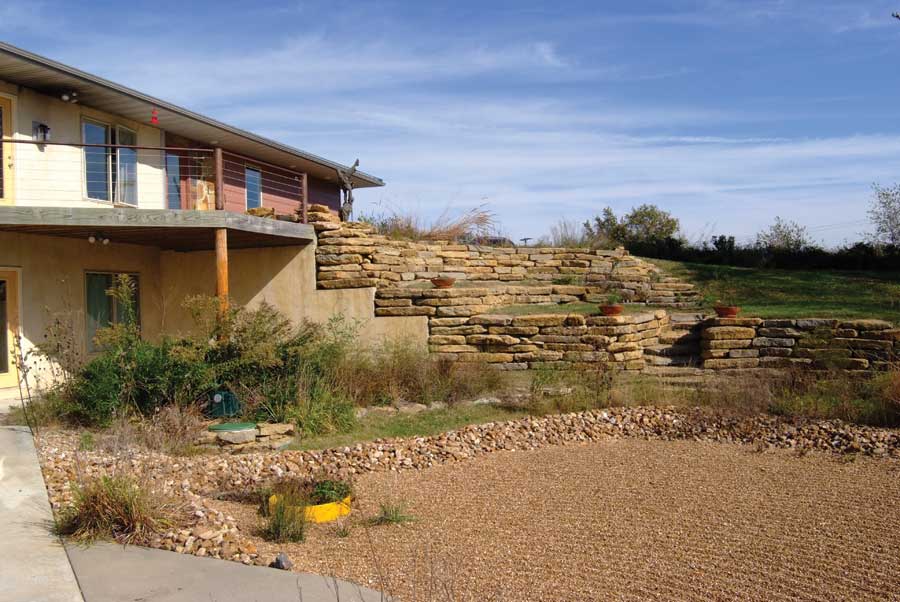 Bermed into the hillside, the home's back side angles to the ground through a series of terraced organic vegetable gardens.